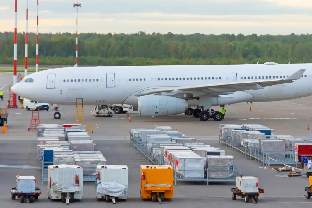 air freight - air cargo lays next to airplane in airport